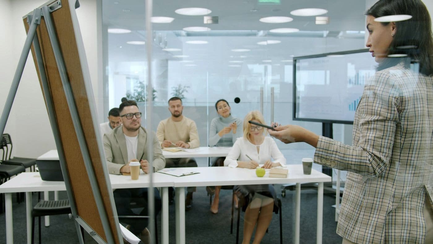 A team lead presenting to colleagues in a bright meeting room