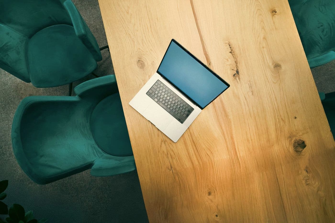 A laptop on a wooden meeting table, ready for a diligence session